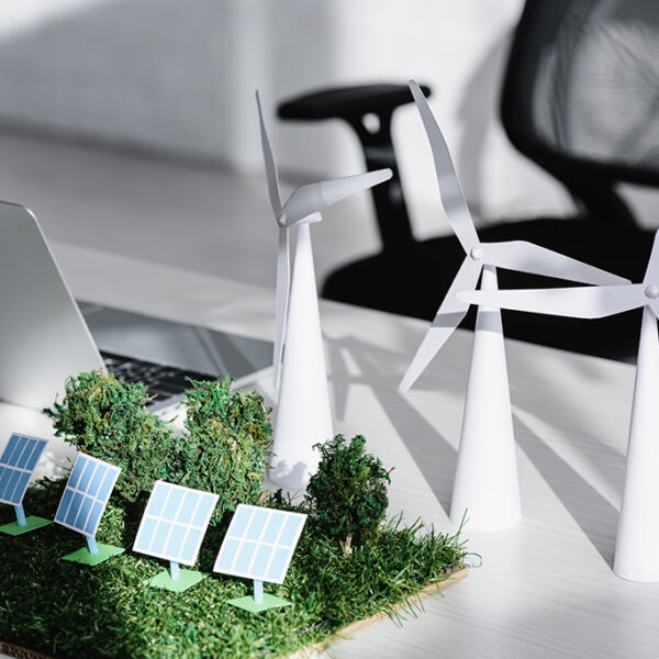 chair near table with laptop, trees, windmills, solar panels models on grass in office
